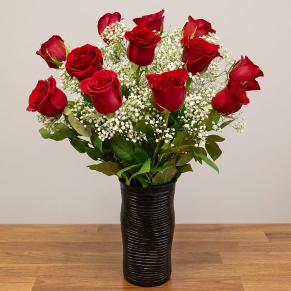 Red roses in a black vase with white filler flowers