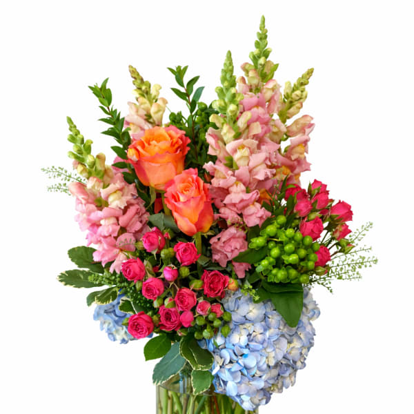 Mixed bouquet of roses, snapdragons, and hydrangeas in a glass vase