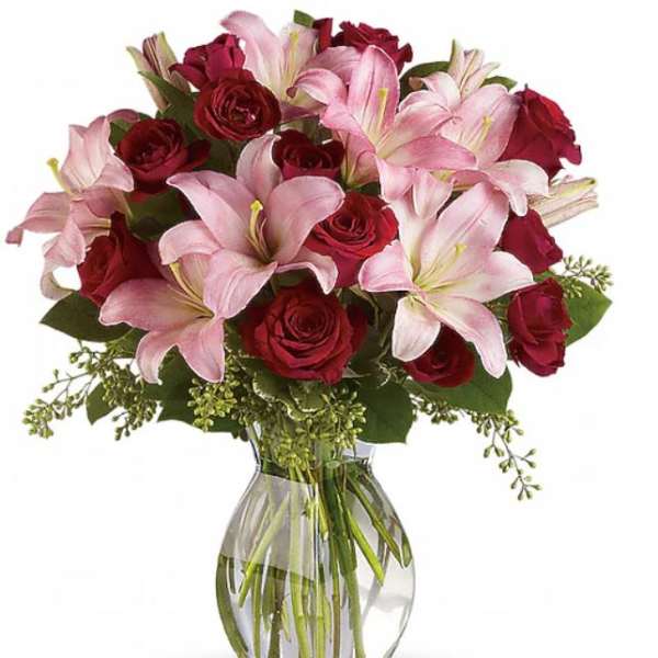 Bouquet of pink lilies and red roses in a clear glass vase