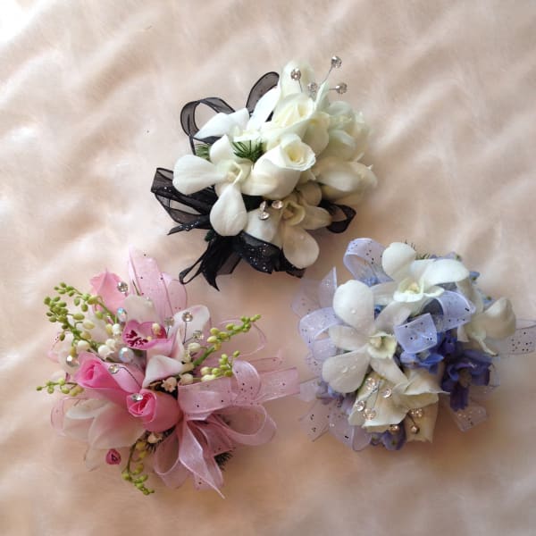 Three small floral corsages with white, pink, and lavender flowers