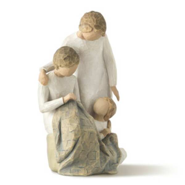 Three carved figurines in white robes, one seated and two standing close together