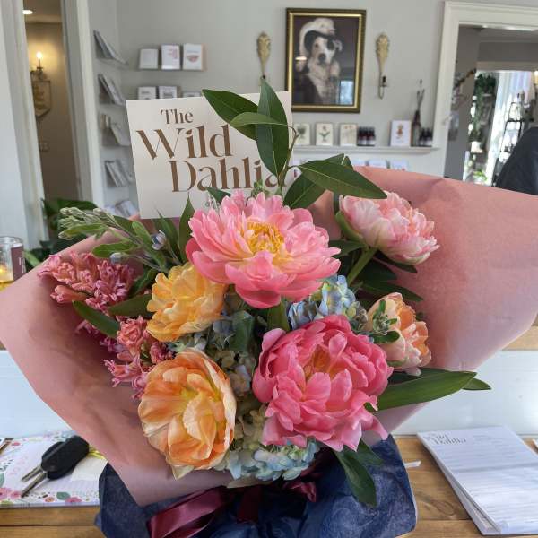 Bouquet of pink, peach, and yellow flowers wrapped in pink paper