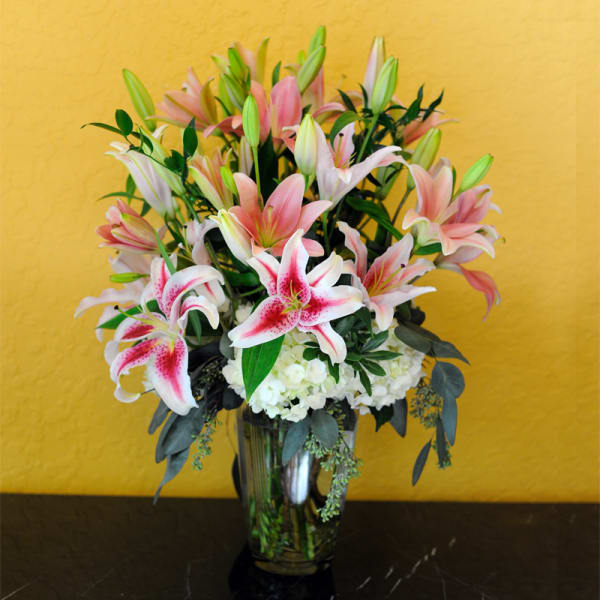 Pink and white lilies arranged in a clear glass vase
