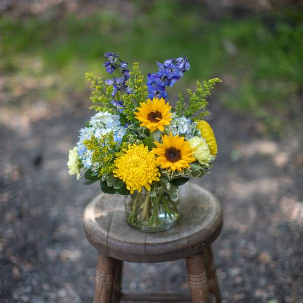 Mixed bouquet in a clear glass vase with yellow sunflowers and blue flowers