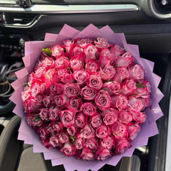 Large bouquet of pink roses wrapped in lavender paper