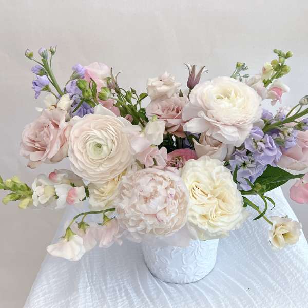 Pastel bouquet of roses and ranunculus in a white vase