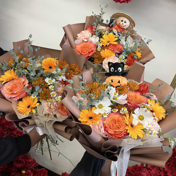 Three mixed flower bouquets with a small plush pumpkin cat and scarecrow topper