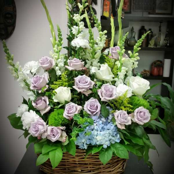 Basket arrangement of lavender and white roses with blue hydrangea