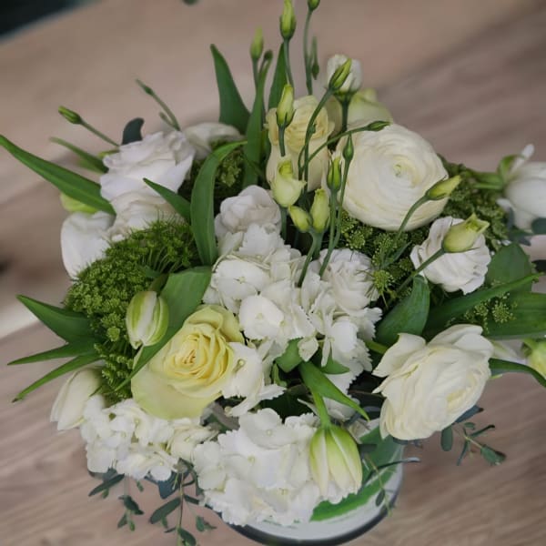 White floral bouquet with roses, ranunculus, and lisianthus in a vase