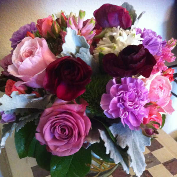 Mixed bouquet of roses, carnations, and daisies in a glass vase