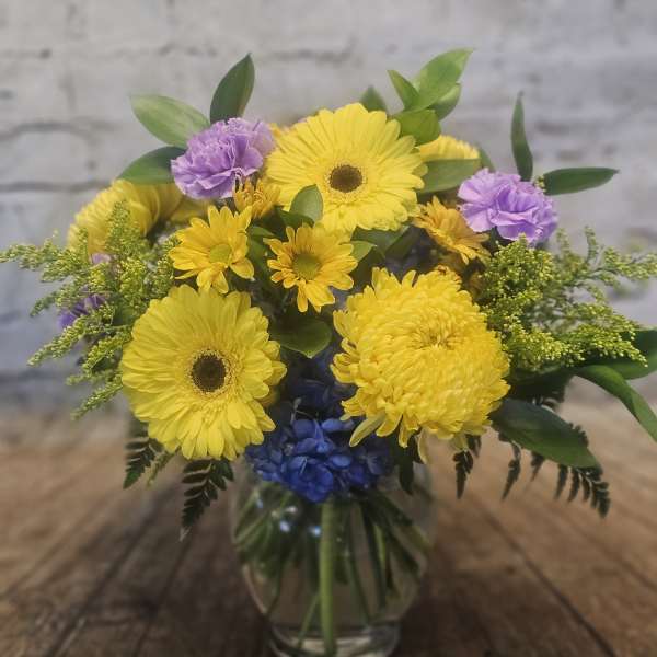 Yellow and purple mixed bouquet in a clear glass vase