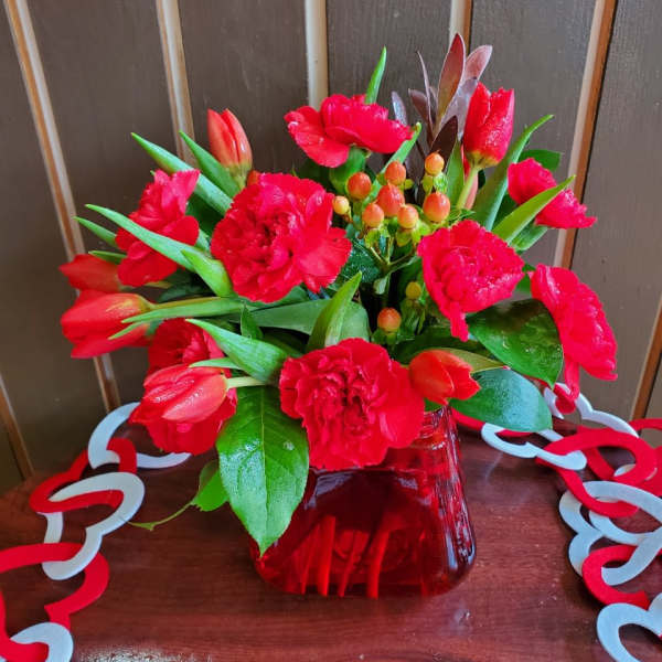 Red tulips and carnations in a red glass vase