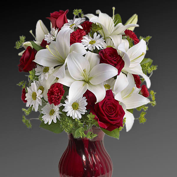 Red roses and white lilies in a red glass vase