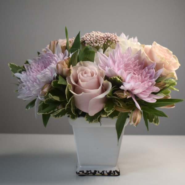 Pink and lavender flowers arranged in a white vase