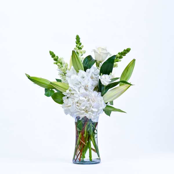 White flowers and lily buds arranged in a clear glass vase