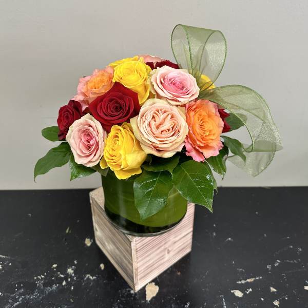 Mixed roses in a green vase with a sheer ribbon bow