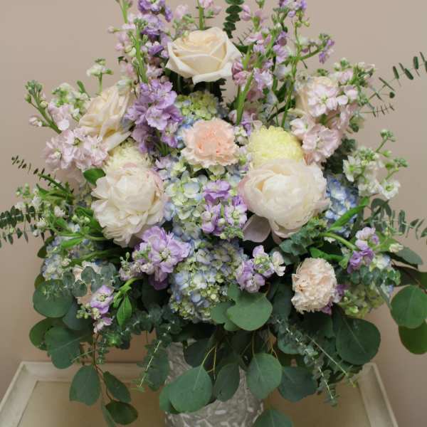 Pastel bouquet of white roses, hydrangeas, and lavender blooms in a metal vase