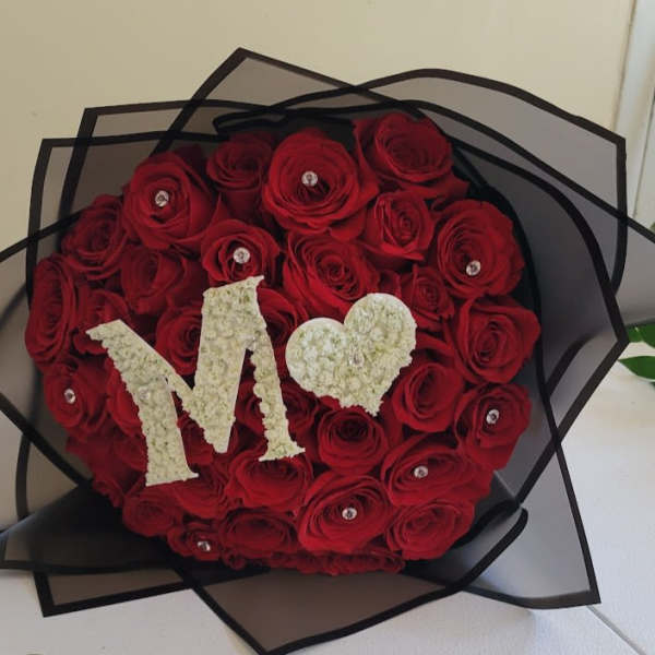 Heart-shaped bouquet of red roses with a white "M" and heart topper