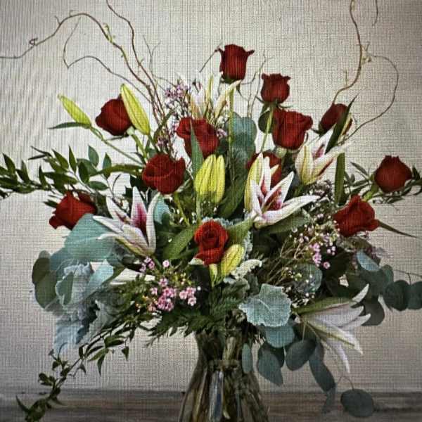 Red roses and lilies in a clear glass vase