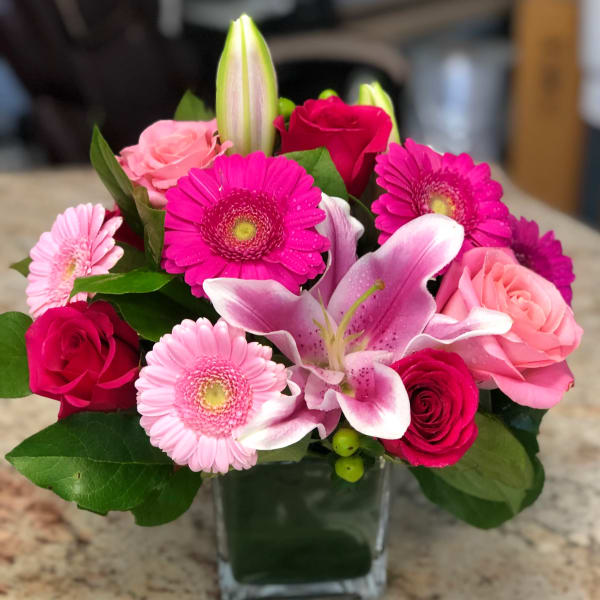 Pink and magenta bouquet with lilies and gerbera daisies in a glass vase