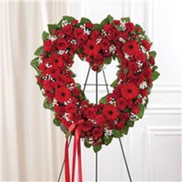Heart-shaped red flower wreath on a stand with a ribbon