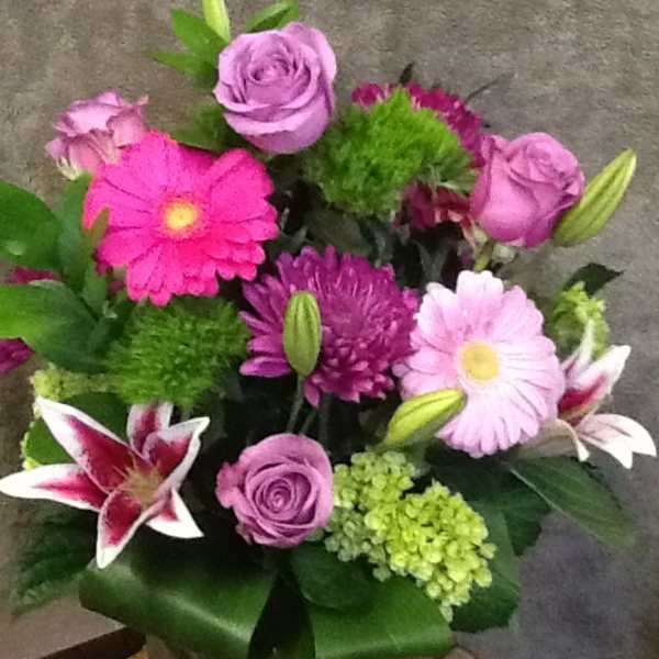 Mixed bouquet of pink and purple flowers in a glass vase