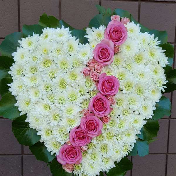 Heart-shaped floral spray of white chrysanthemums and pink roses on a stand