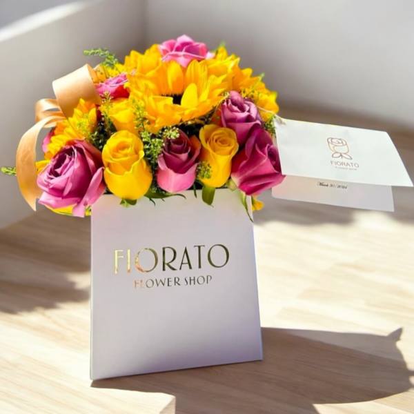 Bouquet of yellow sunflowers and pink roses in a white gift box