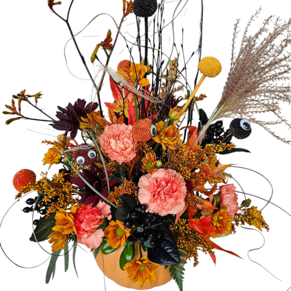 Autumn floral arrangement in a pumpkin-shaped container with pink and orange blooms