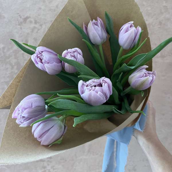 Bouquet of pale lavender tulips wrapped in brown paper with a blue ribbon