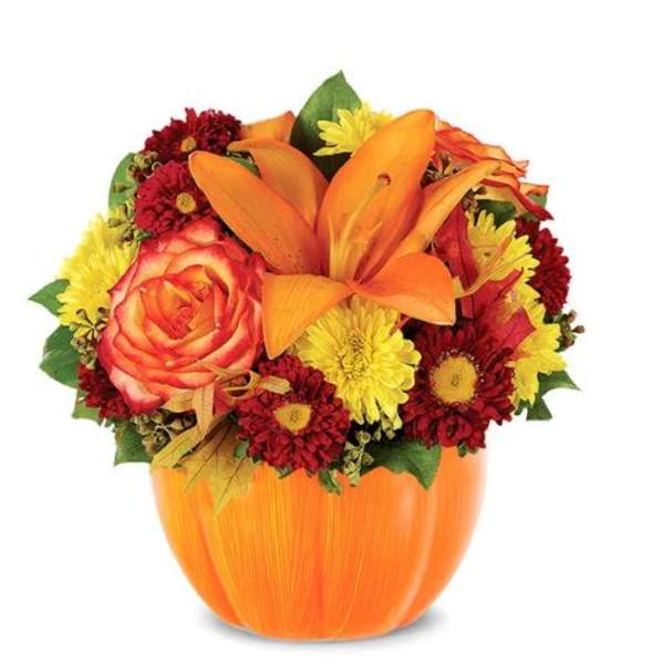 Orange lily and mixed flowers arranged in a pumpkin-shaped vase