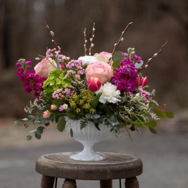Pink and white floral arrangement in a white pedestal vase