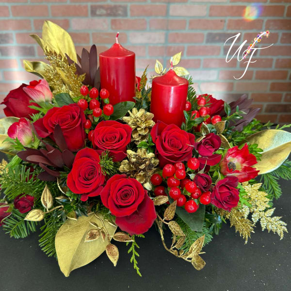 Red roses arranged with two red candles and gold accents