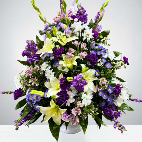 Large bouquet of white lilies, purple flowers, and white daisies in a vase