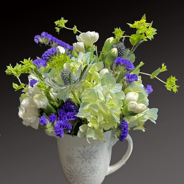 White and purple flowers arranged in a snowflake mug vase