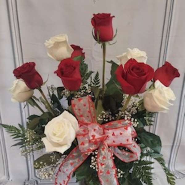 Red and white roses in a glass vase with a heart ribbon