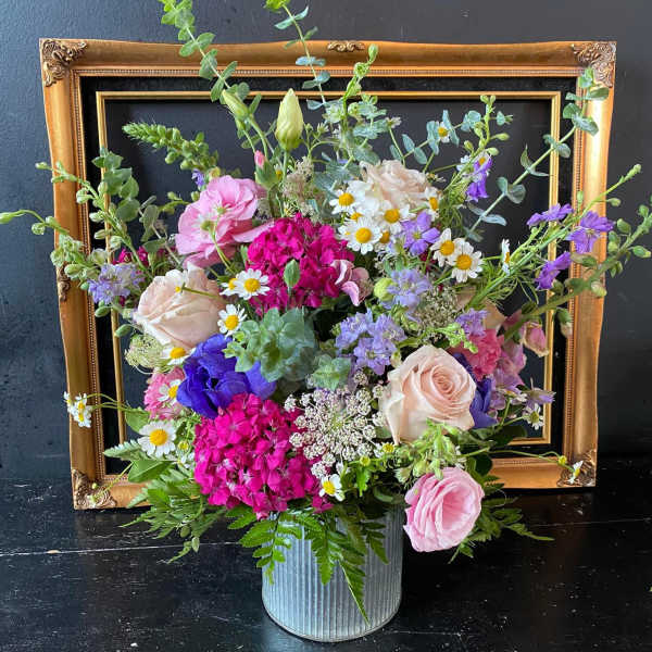 Mixed pink, purple, and white flowers in a ribbed metal container