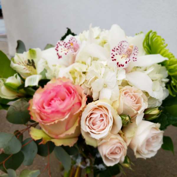 Bouquet of pink and white roses with white orchids in a glass vase