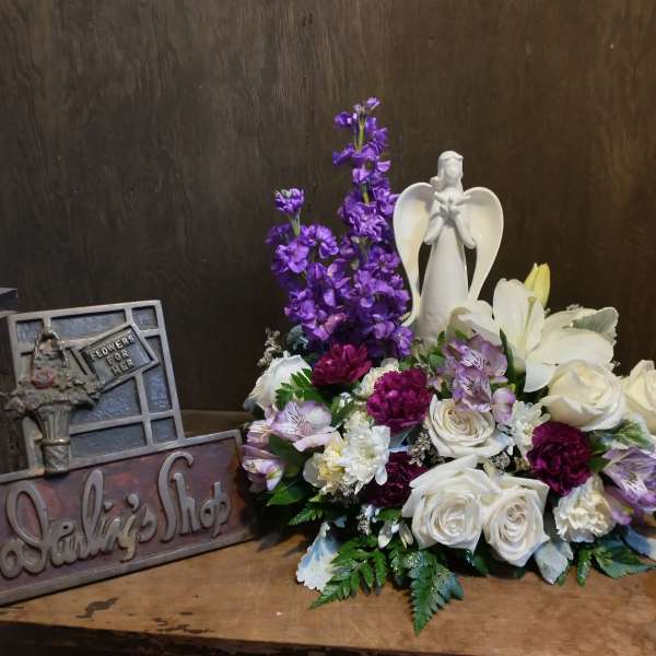 Purple and white floral arrangement with an angel figurine