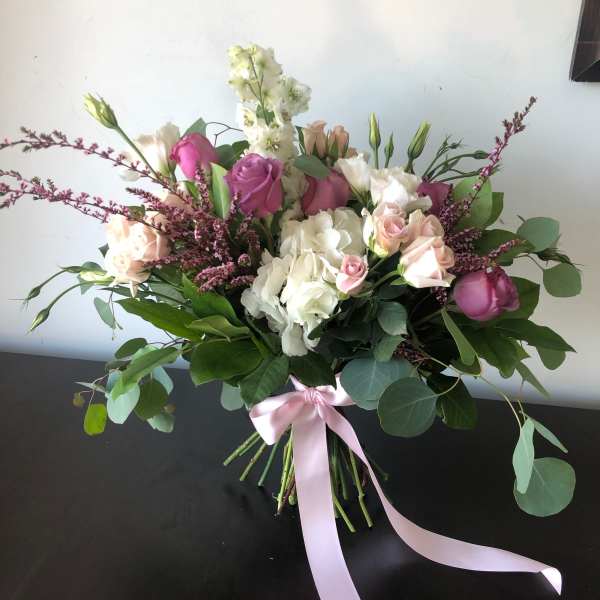Bouquet of pink and white roses with greenery tied with a pink ribbon