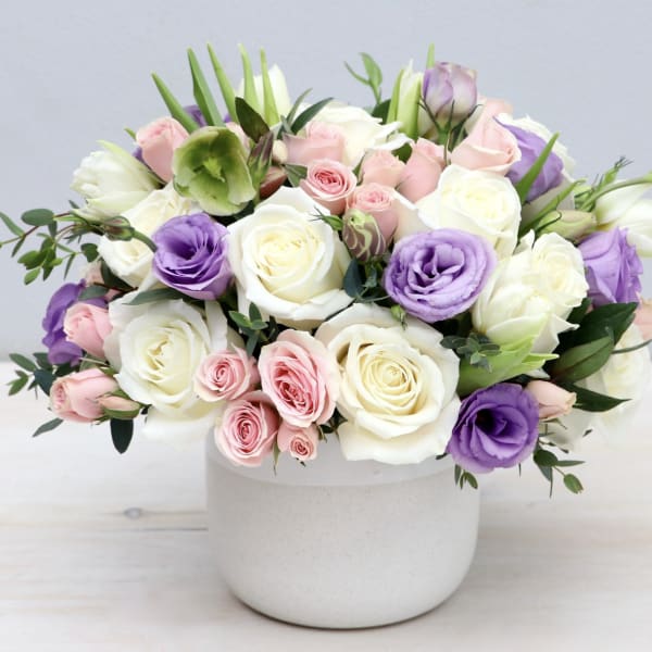 Bouquet of white, pink, and purple roses in a white vase