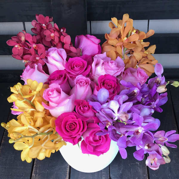 Colorful bouquet of roses and orchids in a white vase