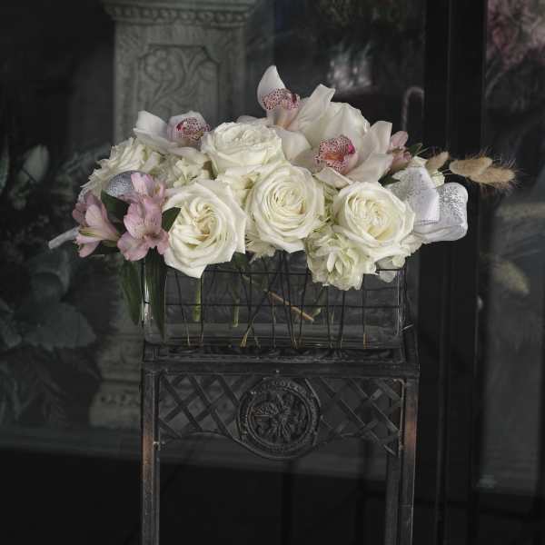 White roses and pink orchids arranged in a rectangular container