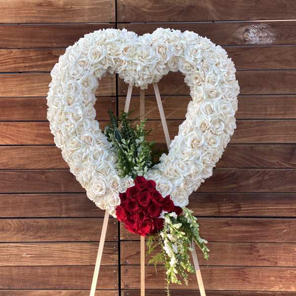 Heart-shaped floral wreath of white and red roses on an easel