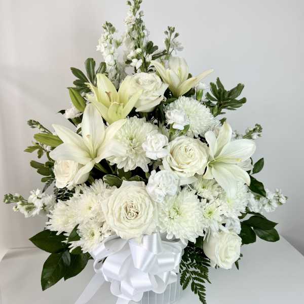 White floral arrangement with lilies, roses, and chrysanthemums in a white vase