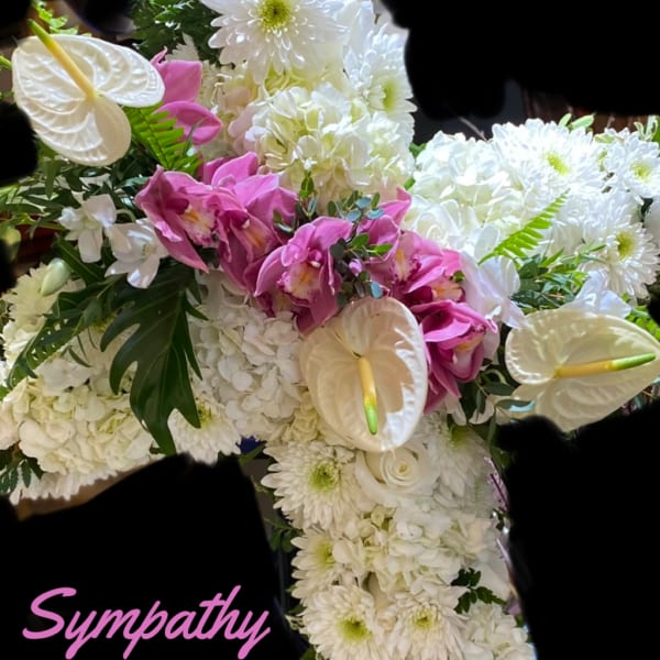 Sympathy cross covered in white flowers with pink orchids