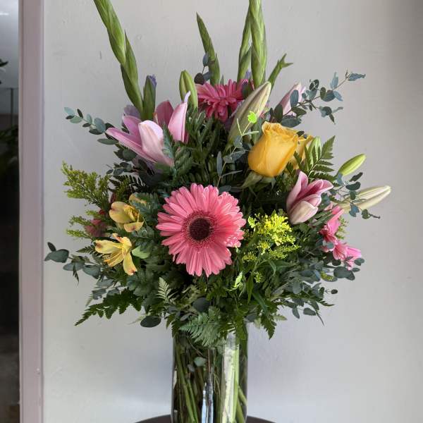 Mixed bouquet in a glass vase with pink, yellow, and white flowers