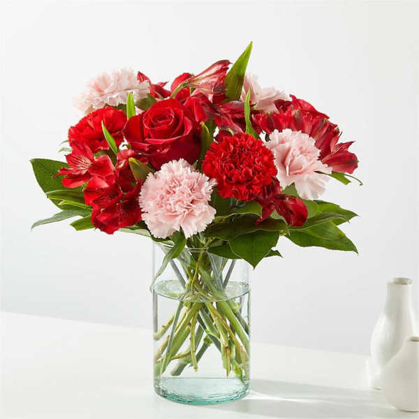Red roses and pink carnations in a clear glass vase