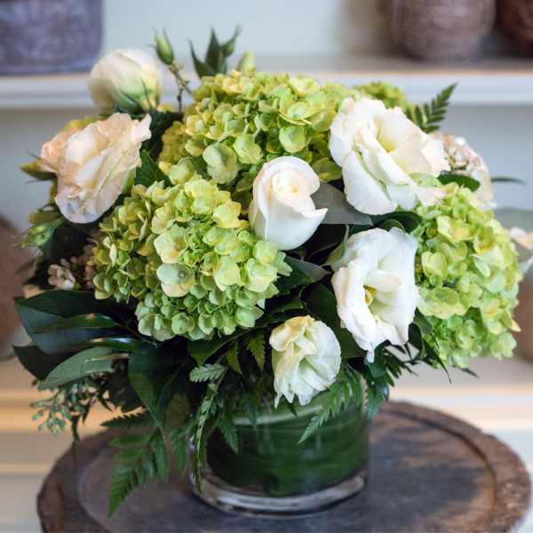 White roses and green hydrangeas in a glass vase