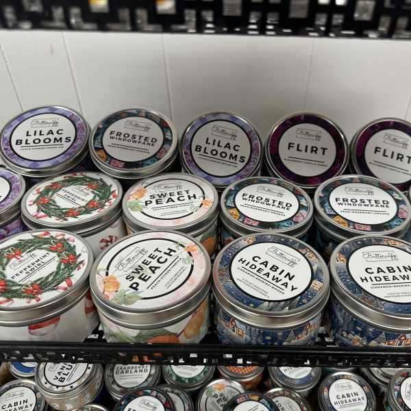 Shelf of scented candles in round metal tins with assorted labels